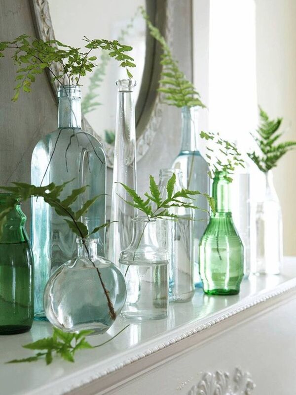 Clear glass bottle of water on a bright table near a plant